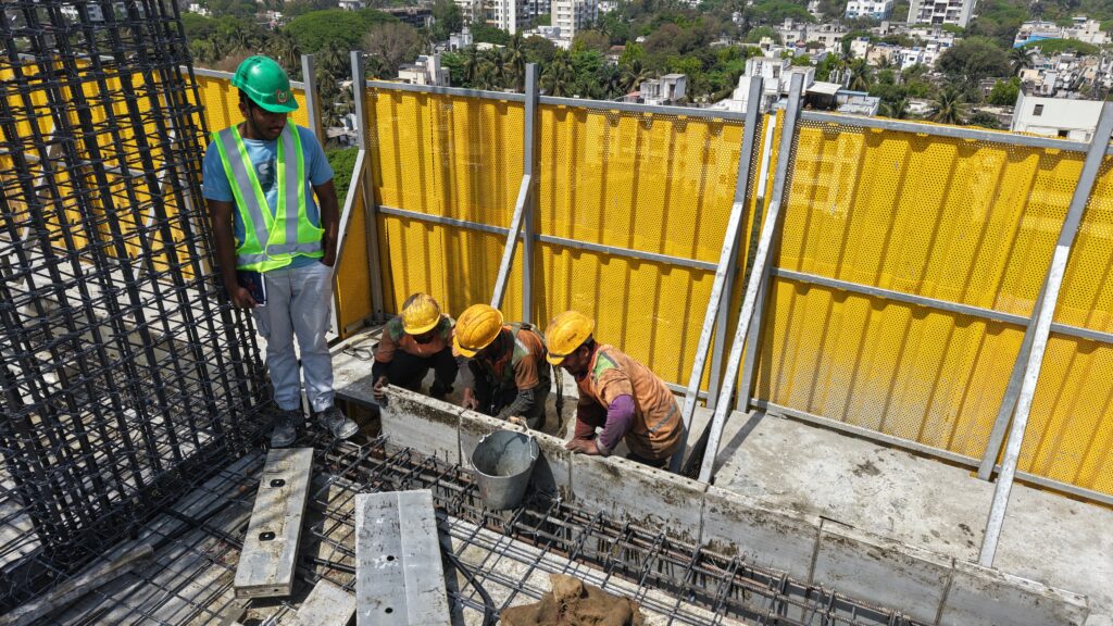 Workers safely performing construction work using safety screen systems.